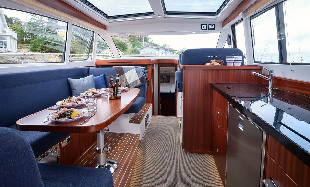 Interior of a luxurious boat featuring a dining area with seafood dishes, drinks, and a modern kitchen layout.